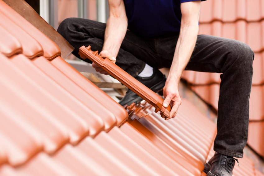Handwerker erneuert Dachziegel