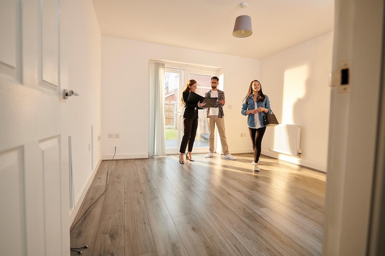 Makler zeigt einem Paar einen Raum in einem Haus zur Vermietung bei einem Besichtigungstermin