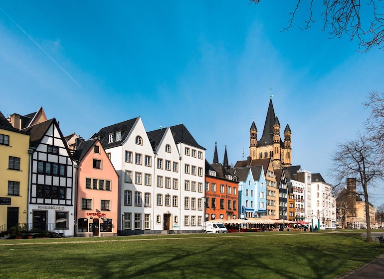 Verschiedene Häuser an einer belebten Straße mit Grünfläche