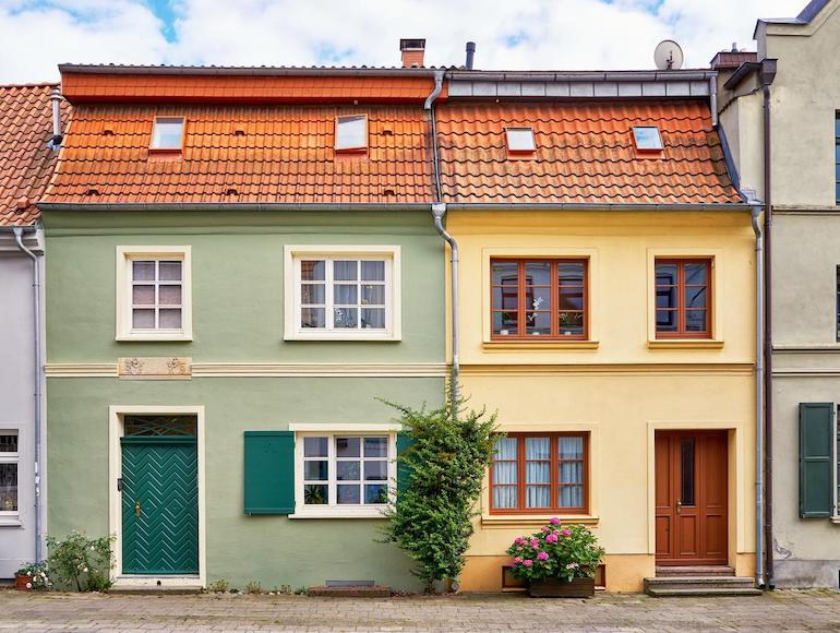 Bunte Häuserreihe von vorne oder leicht erhöht, die Linien der Häuser sind gerade.
